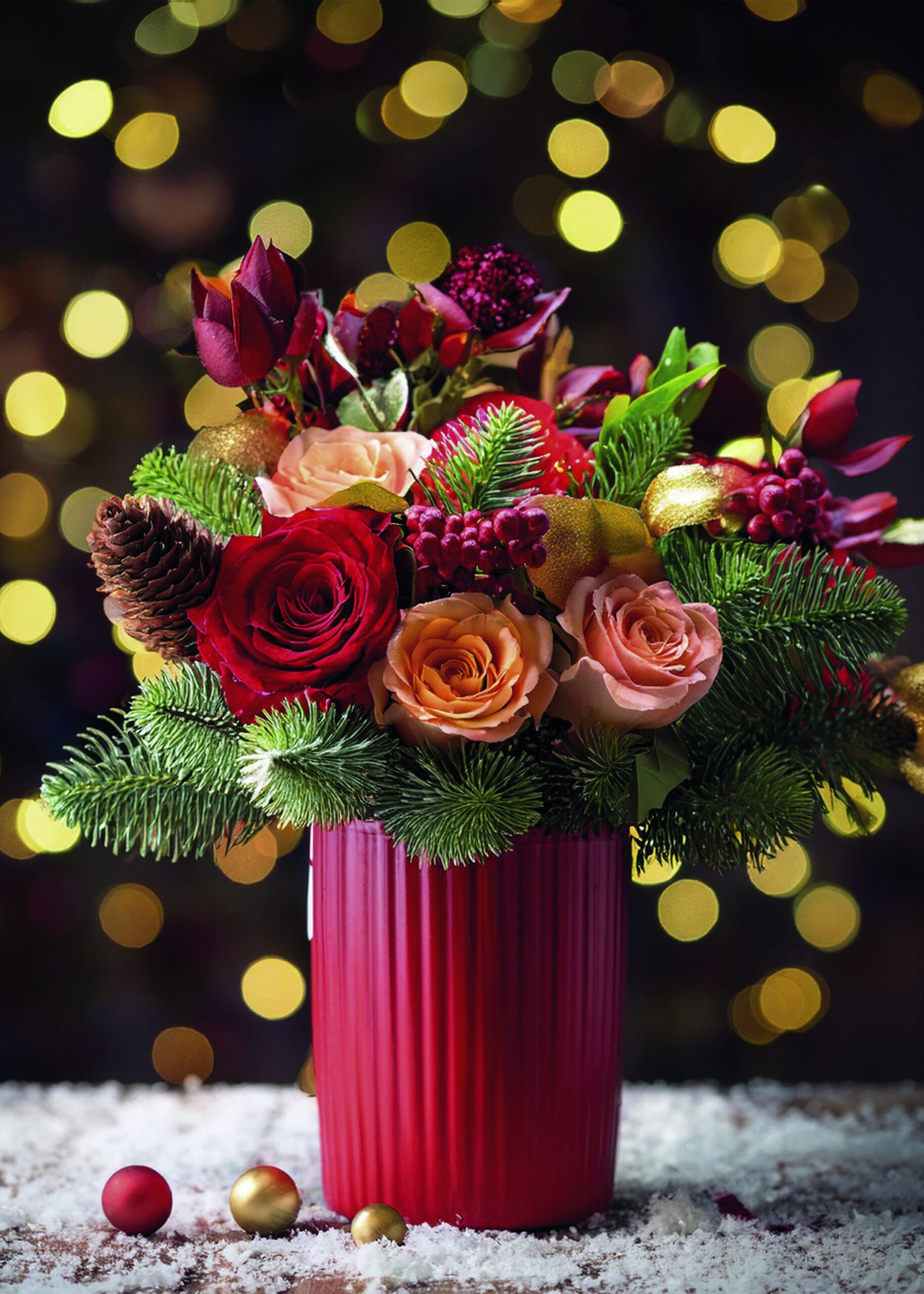Arreglo festivo con rosas rojas y durazno y follaje de temporada